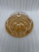 Two round cake stands of different sizes on a white kitchen counter, featuring natural wooden bamboo bases and clear ribbed acrylic dome covers with decorative crystal knobs, containing fruit cakes.