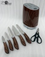 A 6-piece kitchen knife set featuring stainless steel blades with dark wood-grain patterned handles and a matching oval storage block on a granite countertop.