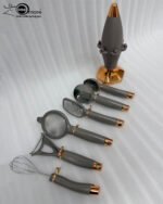 A professional 7-piece kitchen gadget set with rose gold and black ergonomic handles, featuring a pizza cutter, whisk, and grater, organized on a sleek black rotating stand.