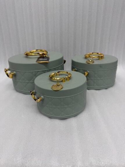 A set of three round, quilted insulated hotpots in varying sizes (1L, 2.5L, and 4L) with gold handles and lid accents, displayed on a kitchen counter and wooden dining table.