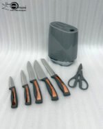 A modern 6-piece kitchen knife set by OneMore featuring grey ergonomic handles with copper accents, displayed both inside a sleek grey storage block on a granite countertop and laid out on a white surface to show the stainless steel blades and matching kitchen shears.