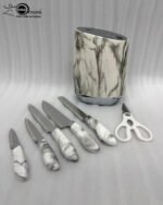 A 6-piece kitchen knife set featuring white and grey marble-patterned handles and a matching oval storage block, displayed on a granite countertop.