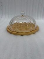 Two round cake stands of different sizes on a white kitchen counter, featuring natural wooden bamboo bases and clear ribbed acrylic dome covers with decorative crystal knobs, containing fruit cakes.
