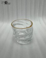 A set of six clear crystal drinking glasses featuring a unique twisted, rippled texture and a thin decorative gold rim on a neutral background.