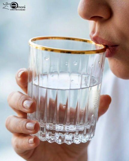 A close-up of a person holding a premium RCR-inspired crystal glass with a luxury gold rim and intricate geometric cut patterns.