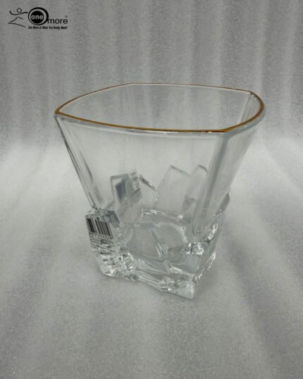 A close-up of a premium RCR-inspired crystal whiskey glass with a textured ice-like geometric base and a thin golden outline on the rim, being used to drink water.