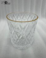 Close-up of a person drinking from an RCR-inspired crystal water glass featuring a textured diamond-cut pattern and a luxurious golden rim.