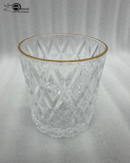 Close-up of a person drinking from an RCR-inspired crystal water glass featuring a textured diamond-cut pattern and a luxurious golden rim.