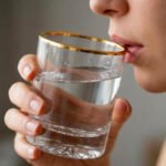 A close-up of a person drinking from a clear crystal glass with a gold-trimmed rim, alongside a studio shot of the glass showcasing a textured swirl pattern on the base.