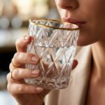 A set of six crystal-clear drinking glasses featuring a deep diamond-cut textured pattern and a thin, elegant gold metallic rim.
