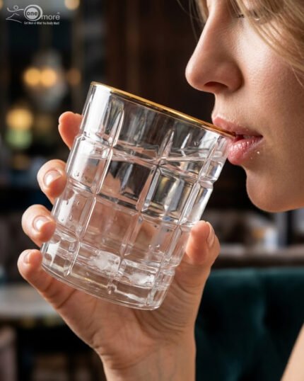 Close-up of a person drinking from a textured RCR-inspired crystal water glass with a luxurious gold rim and geometric square pattern.