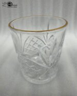 Close-up of a person drinking from a luxurious RCR-inspired crystal glass featuring an intricate diamond-cut pattern and a polished golden rim.
