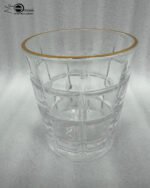 Close-up of a person drinking from a textured RCR-inspired crystal water glass with a luxurious gold rim and geometric square pattern.