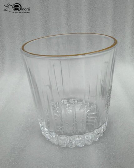 A close-up of a person holding a premium RCR-inspired crystal glass with a luxury gold rim and intricate geometric cut patterns.