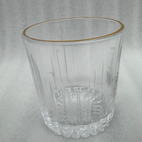 A close-up of a person holding a premium RCR-inspired crystal glass with a luxury gold rim and intricate geometric cut patterns.