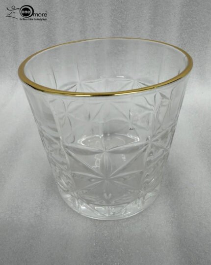 Close-up of a hand holding an RCR-inspired crystal water glass with a geometric starburst pattern and a decorative gold rim.