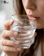 A set of six clear crystal drinking glasses featuring a unique twisted, rippled texture and a thin decorative gold rim on a neutral background.