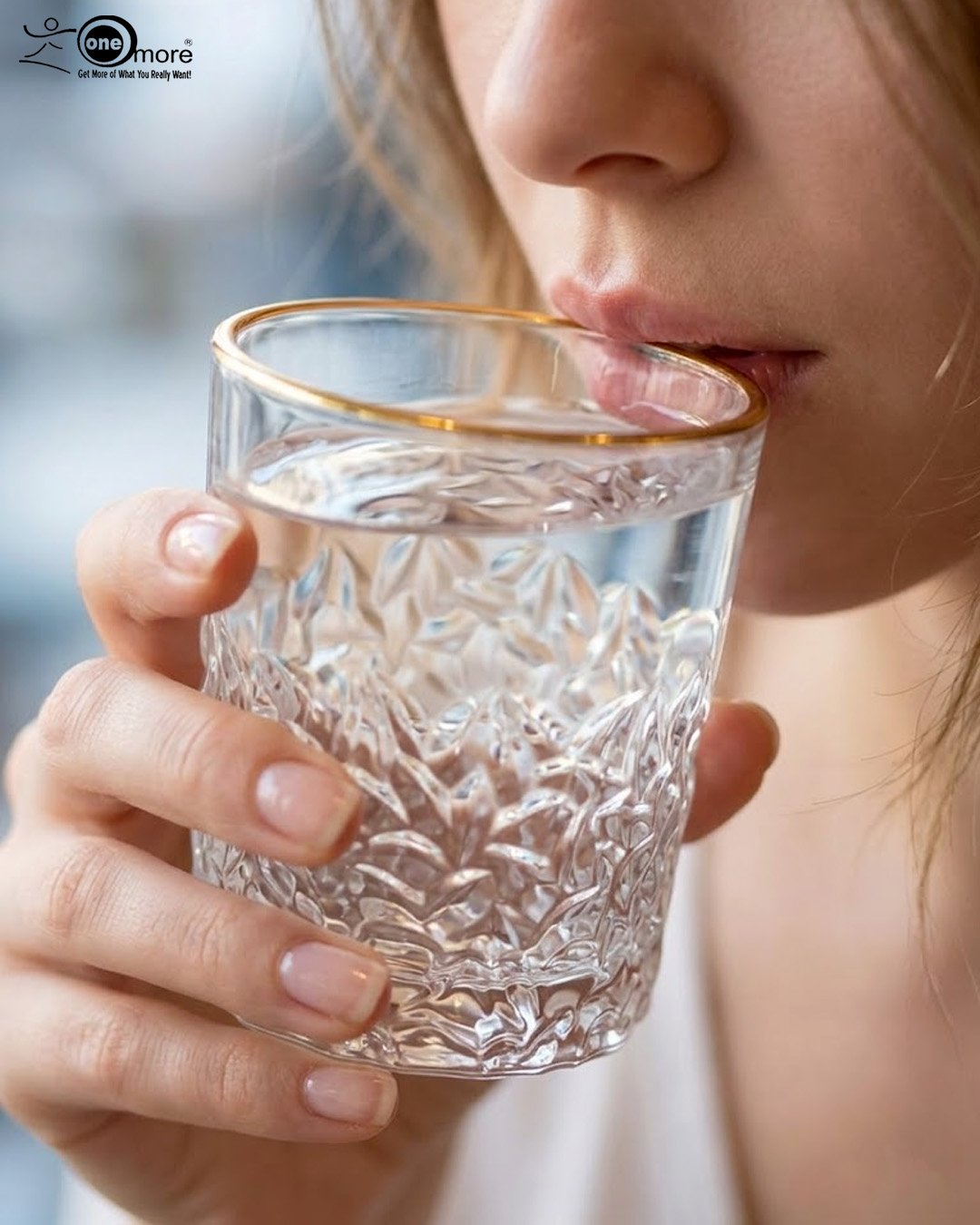 2 A close-up of a person holding a clear crystal water glass with a textured diamond pattern and a thin golden rim, showcasing the elegant light refraction through the water.