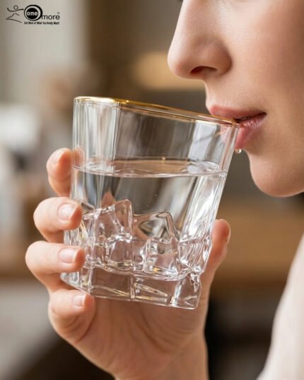 A close-up of a premium RCR-inspired crystal whiskey glass with a textured ice-like geometric base and a thin golden outline on the rim, being used to drink water.