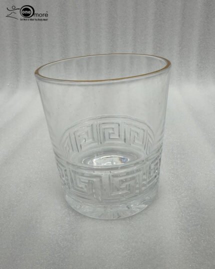 Close-up of a person drinking from a Versace-inspired crystal glass featuring an embossed Greek Key pattern and a luxury golden rim.