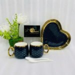 Five-piece stoneware couple set featuring two polka-dotted mugs with gold handles, a matching heart-shaped tray, and two white spoons, available in black, navy, sky blue, pink, and white.