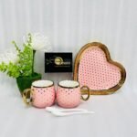 Five-piece stoneware couple set featuring two polka-dotted mugs with gold handles, a matching heart-shaped tray, and two white spoons, available in black, navy, sky blue, pink, and white.