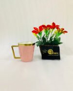 A luxury hexagonal ceramic coffee mug with gold marble veining, featuring a gold-plated square handle and rim, displayed next to a small potted plant with red flowers.