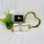 A luxury 5-piece stoneware coffee set for couples featuring two mugs with gold lattice patterns, a matching heart-shaped tray with gold trim, and two white spoons, available in multiple colors including black, green, and pink.