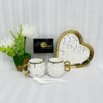 A luxury 5-piece stoneware coffee set for couples featuring two round marble-patterned mugs with gold handles, two white spoons, and a matching heart-shaped gold-rimmed tray, available in black, white, green, blue, and yellow.