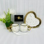 A 5-piece stoneware couple's coffee set featuring two star-patterned mugs with gold handles, two white spoons, and a matching gold-rimmed heart-shaped tray on a clean white background.