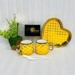 A luxury 5-piece stoneware coffee set for couples featuring two mugs with gold lattice patterns, a matching heart-shaped tray with gold trim, and two white spoons, available in multiple colors including black, green, and pink.