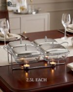 A luxurious Paramount Series 5-in-1 food warmer set on a wooden dining table, featuring four 2.5L glass serving dishes with polished stainless steel lids and tealight buffet burners underneath.