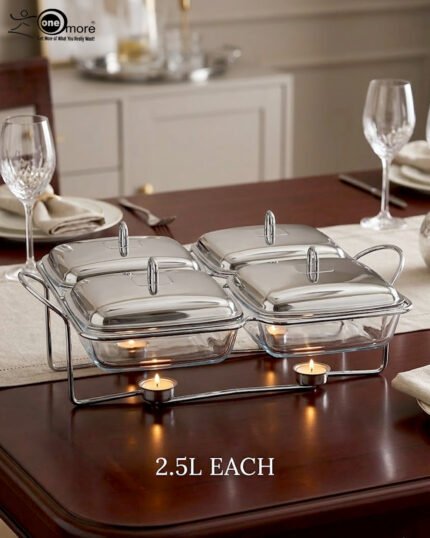 A luxurious Paramount Series 5-in-1 food warmer set on a wooden dining table, featuring four 2.5L glass serving dishes with polished stainless steel lids and tealight buffet burners underneath.