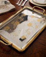 A set of three luxury Onemore brand stainless steel serving trays with gold-textured handles and borders, featuring etched floral patterns on a mirror-polished surface, displayed on a dark wooden dining table.