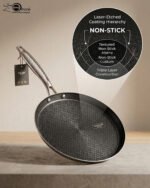 A professional-grade laser-etched non-stick stainless steel crepe pan with a textured honeycomb surface and ergonomic silver handle, shown on a kitchen counter and an induction cooktop.