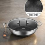 High-angle shot of two Uakeen stainless steel non-stick woks in 30cm and 32cm sizes on a wooden countertop, showing the laser-etched hexagonal interior and tempered glass lids.