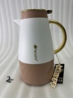 Three elegant 1.5-liter stainless steel thermal flasks in rose gold, slate grey, and charcoal blue bases with white bodies and gold-plated handles, displayed on a marble kitchen countertop.