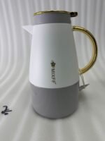 Three elegant 1.5-liter stainless steel thermal flasks in rose gold, slate grey, and charcoal blue bases with white bodies and gold-plated handles, displayed on a marble kitchen countertop.