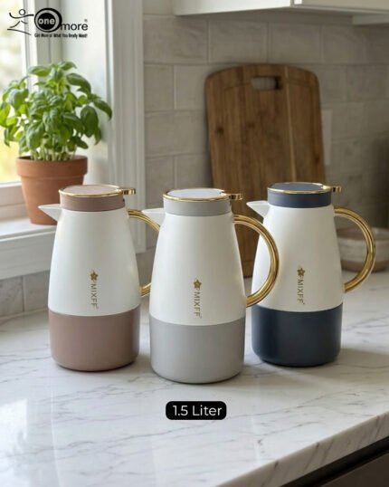 Three elegant 1.5-liter stainless steel thermal flasks in rose gold, slate grey, and charcoal blue bases with white bodies and gold-plated handles, displayed on a marble kitchen countertop.