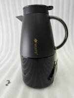 Three 2-liter luxury stainless steel thermal flasks in black, cream, and grey finishes with metallic handles, arranged on a white marble kitchen counter.