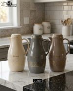 A trio of elegant 2-liter Feenik thermal flasks in cream, grey, and taupe featuring gold floral patterns on a marble kitchen countertop.