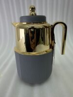 Three luxury 1-liter thermal flasks in white, grey, and black with polished gold tops and ribbed textured bases on a marble kitchen counter.