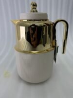 Three luxury 1-liter thermal flasks in white, grey, and black with polished gold tops and ribbed textured bases on a marble kitchen counter.