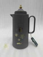 Three 1-liter DayDays insulated flasks in white, taupe, and grey, featuring gold floral designs and decorative gold lids on a kitchen counter.