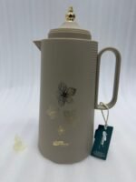 Three 1-liter DayDays insulated flasks in white, taupe, and grey, featuring gold floral designs and decorative gold lids on a kitchen counter.