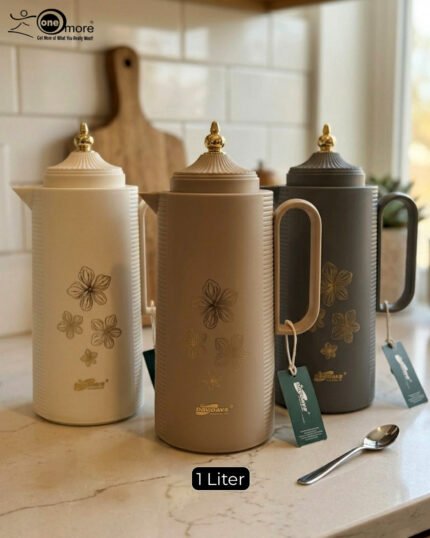 Three 1-liter DayDays insulated flasks in white, taupe, and grey, featuring gold floral designs and decorative gold lids on a kitchen counter.