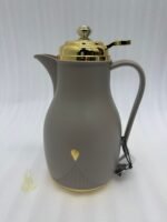 Three 1-liter thermal flasks in grey, beige, and white featuring matte finishes, elegant gold lids, and ergonomic handles on a marble countertop.