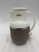 Three 1-liter modern vacuum flasks with cream-colored tops and ribbed bases in brown, grey, and beige, displayed on a white marble kitchen countertop.