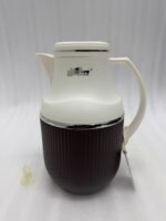 Three 1-liter modern vacuum flasks with cream-colored tops and ribbed bases in brown, grey, and beige, displayed on a white marble kitchen countertop.