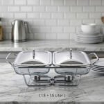 A Paramount Series 2-in-1 stainless steel food warmer with two 1.5-liter glass serving dishes and dual buffet burners, displayed on a marble kitchen countertop.